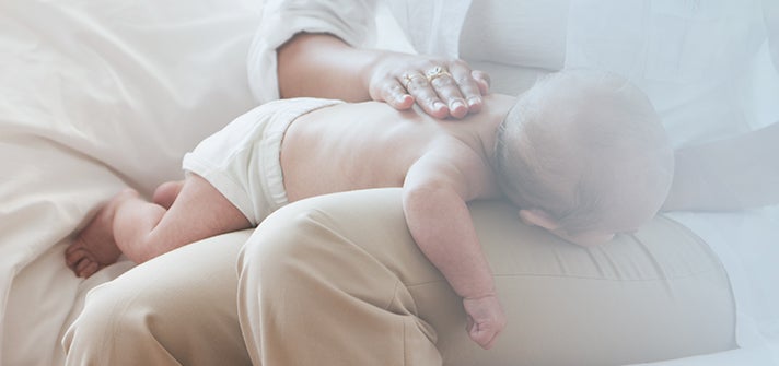 Baby lying on the lap of a parent and doing tummy time
