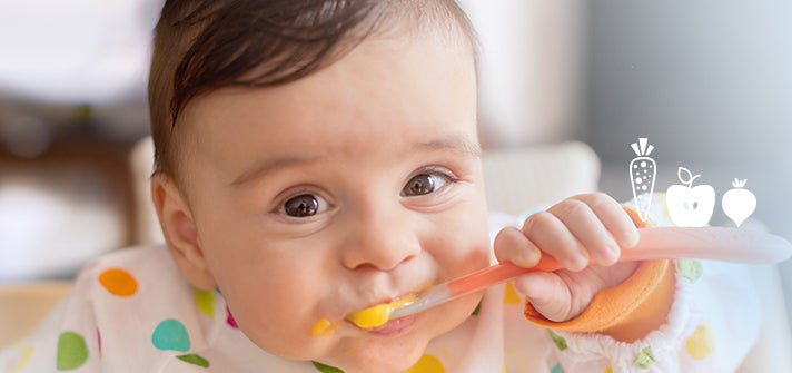 baby spoon feeing themselves puree from a spoon