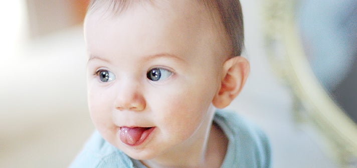 baby sticking out their tongue to someone out of frame