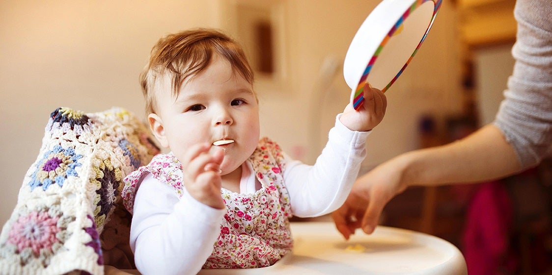 baby eating food and playing with their bowl
