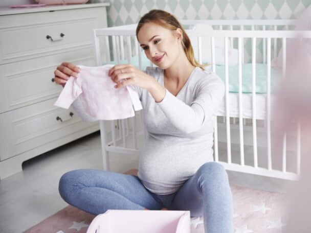 pregnant woman looking at newborn clothes pregnant woman looking at newborn clothes