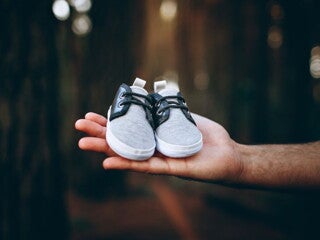 Man holding a pair of baby boots in a forest Man holding a pair of baby boots in a forest