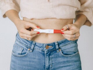 Woman holding a positive pregnancy stick over her stomach Woman holding a positive pregnancy stick over her stomach