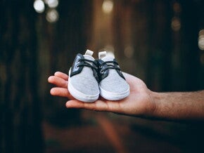Man holding a pair of baby boots in a forest Man holding a pair of baby boots in a forest