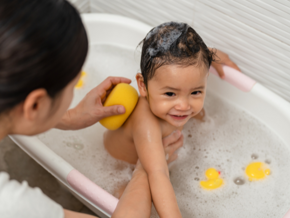 Toddler in a bubble bath with mother holding their body