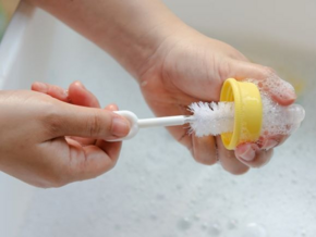 Woman cleaning bottle in sink