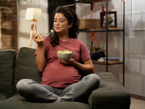 Woman sitting on the lounge eating fruit from a bowl Woman sitting on the lounge eating fruit from a bowl