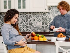 Pregnant woman looking at iPad with man in the kitchen Pregnant woman looking at iPad with man in the kitchen