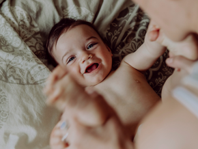 Baby smiling on a bed with his mother