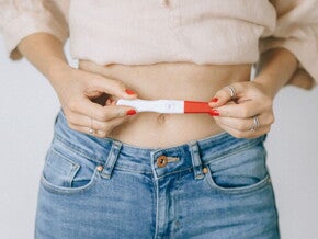 Woman holding a positive pregnancy stick over her stomach Woman holding a positive pregnancy stick over her stomach