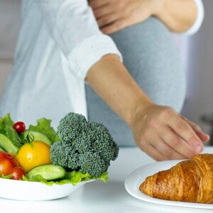 Pregnant woman with a salad and croissant in front of her