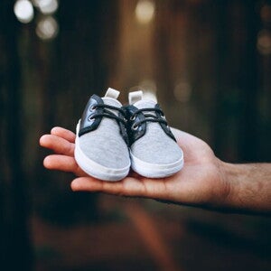 Man holding a pair of baby boots in a forest