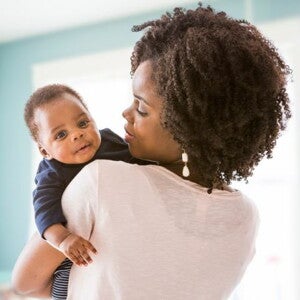 Mother in white tshirt holding her baby who is looking over her shoulder Mother in white tshirt holding her baby who is looking over her shoulder