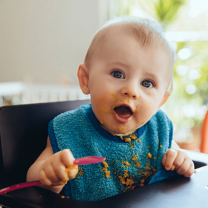 young baby spoon food puree green bib