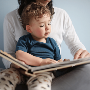 Toddler reading a book on mums lap