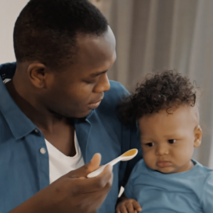 Man feeding baby pureed foods on spoon Man feeding baby pureed foods on spoon