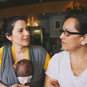 Woman with baby in carrier talking to an older woman