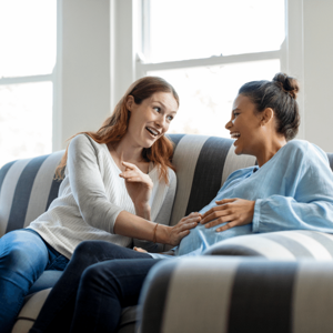 two women laughing one is pregnant
