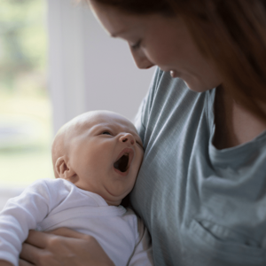 Baby tired yawning in mothers arms
