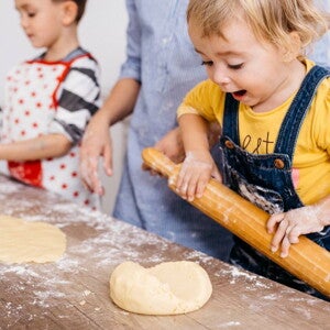 toddlers rolling out dough in the kitchen to cook