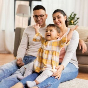 Happy toddler in yellow flannel shirt sitting on their parents Happy toddler in yellow flannel shirt sitting on their parents