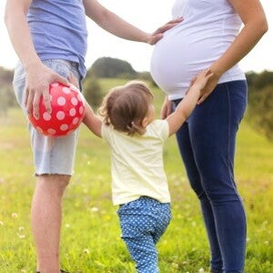 Pregnant woman with man and toddler in a field Pregnant woman with man and toddler in a field