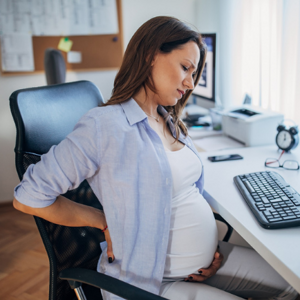 Pregnant woman with back pain at desk