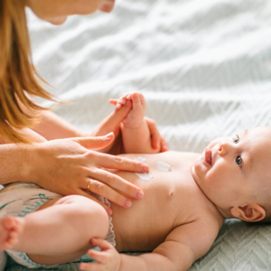 Mother massaging baby laying down with cream