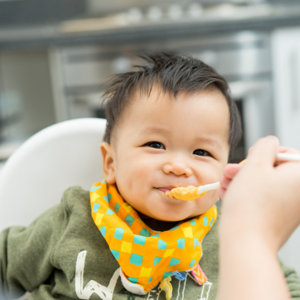 close up image of a toddler eating with bib on