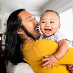 Asian dad holding young laughing baby