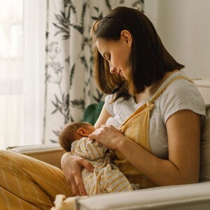 Mother sitting on couch breastfeeding her infant