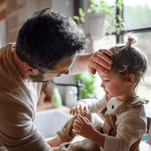 Father putting hand on toddlers forehead to check for fever