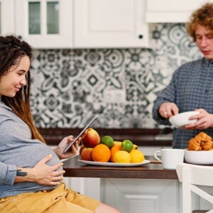 Pregnant woman looking at iPad with man in the kitchen