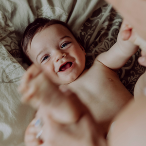 Baby smiling on a bed with his mother