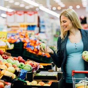 Pregnant woman selecting fresh apples.