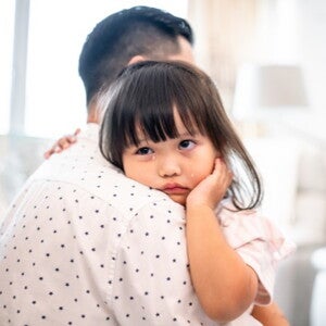 Toddler crying on her dads shoulder
