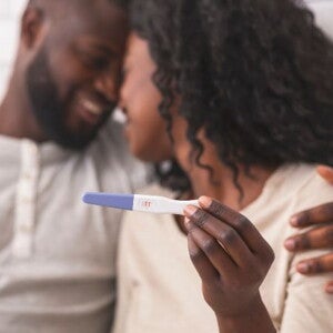 Couple hugging while holding a positive home pregnancy test