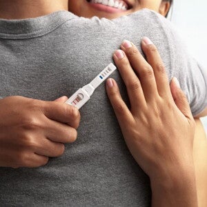 couple hugging with a positive pregnancy test in their hand
