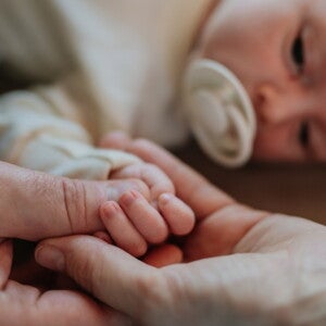 Parents holding their new babies hand while they lie down Parents holding their new babies hand while they lie down