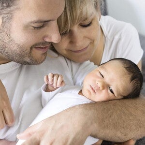 parents in white shirts holding their young baby parents in white shirts holding their young baby