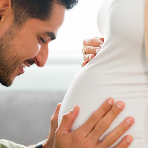 Man hugging womans pregnant stomach Man hugging womans pregnant stomach