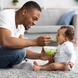 man feeding his child with a spoon man feeding his child with a spoon