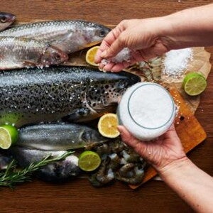 Raw fish being seasoned with salt.