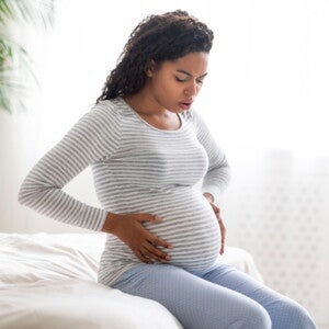 Woman in labour holding her pregnant belly