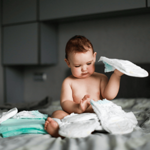 toddler on bed playing with nappies