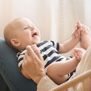 Baby on mothers lap holding mothers hand