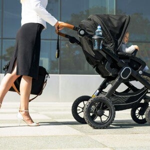mother in business attire walking to work with her baby in a pram