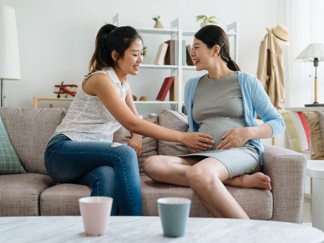 Pregnant woman and friend touching her belly Pregnant woman and friend touching her belly
