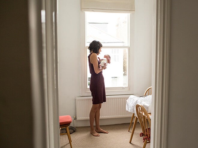 Woman in a black dress holding her baby in a room Woman in a black dress holding her baby in a room