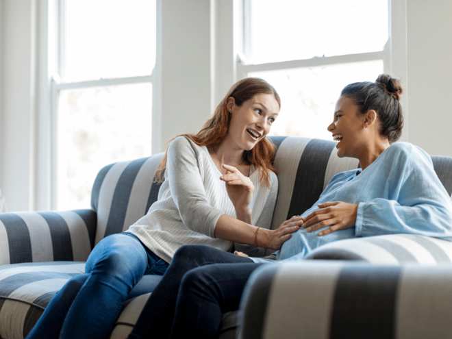 two women laughing one is pregnant two women laughing one is pregnant